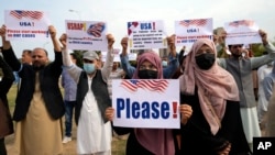 FILE - Afghan refugees protesting delays in relocation approvals by the U.S. government hold placards in Islamabad, Feb. 26, 2023.
