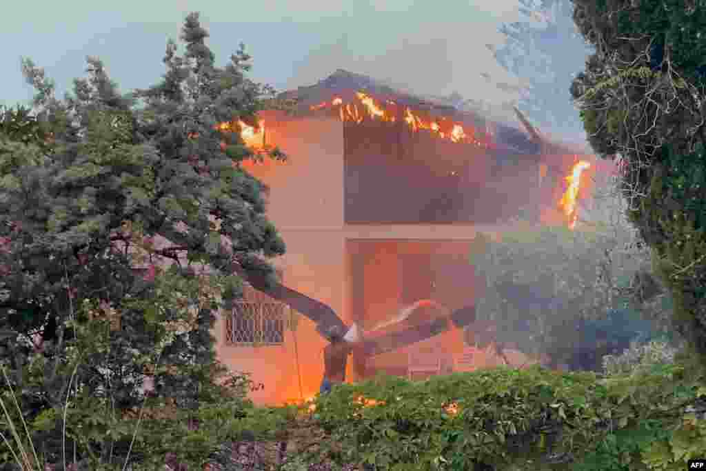 A man extinguish a fire burning a house in the Tono district of Messina, Sicily, Italy, July 26, 2023.