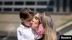 Seorang perempuan tampak mencium anaknya setelah ia mengikuti proses pengambilan sumpah menjadi warga negara AS dalam upacara naturalisasi yang digelar di Perpustakaan Umum New York di Kota New York, pada 2 Juli 2024. (Foto: Reuters/Brendan McDermid)