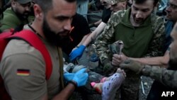 স্বেচ্ছাসেবকরা ২০২৩ সালের ২৭ জুন ক্রামাটোর্স্কে রাশিয়ার ক্ষেপণাস্ত্র হামলার ফলে তৈরি ধ্বংসস্তূপ থেকে এক ব্যক্তিকে নিয়ে যাচ্ছেন।