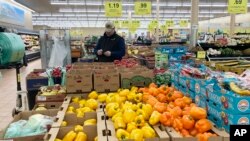 A man looks at his mobile phone while shopping at a grocery store in Buffalo Grove, Ill., Sunday, March 19, 2023.
