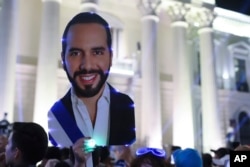 FILE - Supporters hold a cut of Salvador President Nayib Bukele as they gather to celebrate results of a general election at the Gerardo Barrios square in downtown San Salvador, El Salvador, Feb. 4, 2024.
