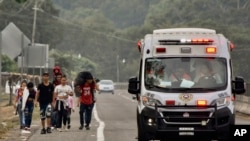 Una ambulancia pasa junto a migrantes que caminan hacia Huehuetán, estado de Chiapas, México, el lunes 24 de abril de 2023.