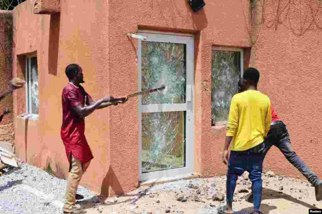 Pro-junta demonstrators break down one of the doors of the French embassy building before being dispersed by Nigerian security forces in Niamey, the capital city of Niger.