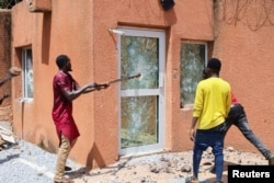 Pro-junta demonstrators break down one of the doors of the French embassy building before being dispersed by Nigerian security forces in Niamey, the capital city of Niger, July 30, 2023.