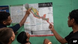 Teenager migrants look at a map of Mexico at the Peace Oasis of the Holy Spirit Amparito shelter in Villahermosa, Mexico, June 7, 2024.
