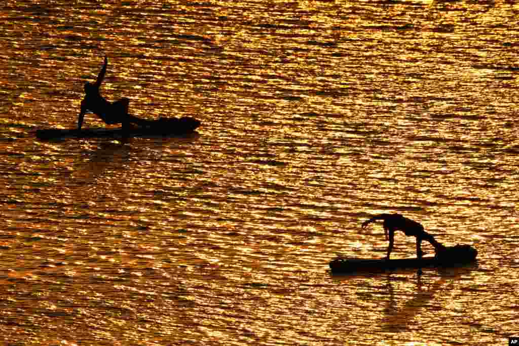 People do yoga poses on paddleboards at sunset as the heat index tops 100&deg; F&nbsp;at Olathe Lake, July 15, 2024, in Olathe, Kansas.