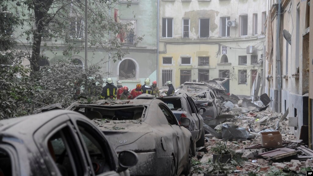 Trabajadores de los servicios de emergencia se reúnen frente a los edificios dañados mientras continúa la búsqueda de víctimas tras un ataque con misiles rusos en Lviv, Ucrania, el 6 de julio de 2023.