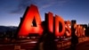 FILE - This picture taken on July 24, 2014 shows people walking past an "AIDS 2014" sign promoting the 20th International AIDS Conference in Melbourne on the eve of concluding session of the conference. 