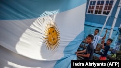 Fans pemain sepak bola Argentina Lionel Messi berdiri di dekat bendera Argentina di luar rumah yang dicat dengan warna nasional negara tersebut, di Desa Karama di Polewali Mandar. (Foto: AFP/Indra Abriyanto)