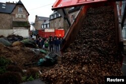 FILE - French farmers dump patatoes and rubbish to block the Sub-Prefecture in Guingamp to protest over price pressures, taxes and green regulation, grievances shared by farmers across Europe, Brittany, France, Jan. 24, 2024.