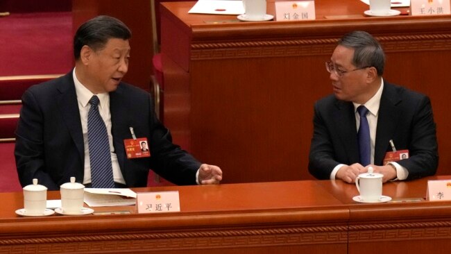 FILE - Chinese President Xi Jinping, left, chats with Chinese Premier Li Qiang during a session of China's National People's Congress at the Great Hall of the People in Beijing, March 12, 2023.