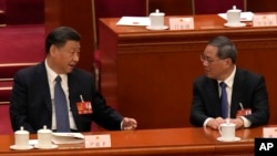 资料照片：中国国家主席习近平2023年3月12日在全国人民代表大会上与中国总理李强交谈。