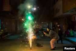 FILE - A woman takes pictures of firework on the eve of the Chinese Lunar New Year, or the Spring Festival, in Lianyungang, Jiangsu province, China January 27, 2017. (REUTERS)