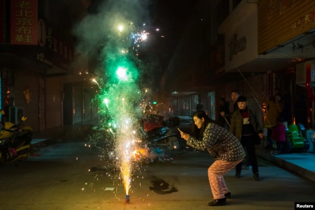 FILE - A woman takes pictures of firework on the eve of the Chinese Lunar New Year, or the Spring Festival, in Lianyungang, Jiangsu province, China January 27, 2017. (REUTERS)