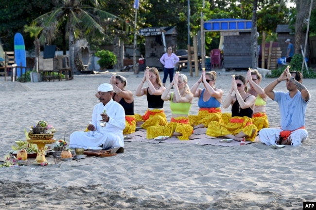 Sejumlah turis mancanegara mengikuti upacara ritual Hindu di pantai di kawasan Seminyak, Bali, 5 Agustus 2023. (Foto: Sonny Tumbelaka/AFP)