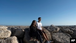 Siblings Sofia Oliveira, 18, and Andre Oliveira, 15, pose for a picture at the beach in Costa da Caparica, south of Lisbon, Sept. 20, 2023.