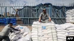 A worker rests as displaced Palestinians receive food aid at the United Nations Relief and Works Agency for Palestine Refugees (UNRWA) center in Rafah in the southern Gaza Strip on Jan. 28, 2024.