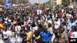 FILE - Civil society groups and political groups hold placards as they march calling on authorities respect the election date, in Dakar, on Feb. 17, 2024.