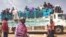 FILE - People board a truck as they leave Khartoum, Sudan, on June 19, 2023.