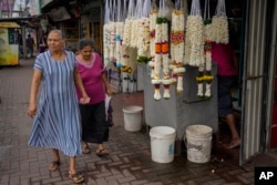 FILE - Elderly women walk past a road side flower seller in Colombo, Sri Lanka, Sept. 27, 2023.