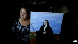 Rita Canteros poses for a picture alongside a painting depicting María Antonia de Paz y Figueroa, more commonly known by her Quechua name of 'Mama Antula,' on the outskirts of Buenos Aires, Argentina, Jan. 28, 2024. 