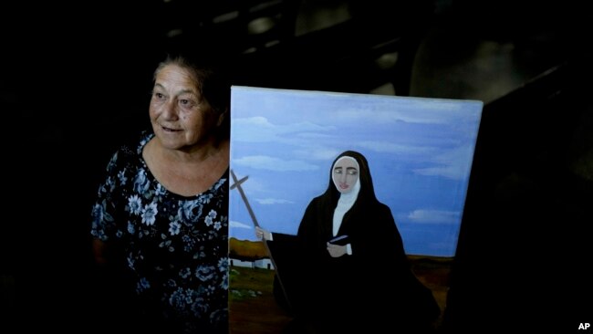 Rita Canteros poses for a picture alongside a painting depicting María Antonia de Paz y Figueroa, more commonly known by her Quechua name of 'Mama Antula,' on the outskirts of Buenos Aires, Argentina, Jan. 28, 2024.