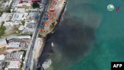 This video grab taken from a handout footage released on Feb. 10, 2024 by the Tobago House Assembly shows emergency workers scramble to clean up a massive oil spill after a mysterious vessel ran aground near the Caribbean island earlier this week in Trinidad and Tobago. 