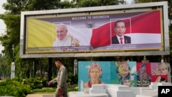 A person walks past a welcoming banner bearing portraits of Pope Francis and Indonesian President Joko Widodo ahead of the pope's visit to Indonesia, in Jakarta, Indonesia, Sept. 3, 2024.