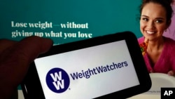 This image shows the logo of WeightWatchers on a mobile phone, and the company's website on March 7, 2023. (AP Photo/Richard Drew)