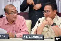 Ketua Komisi Pemilihan Umum (KPU) Hasyim Asyari (kiri) dan Ketua Bawaslu Rahmat Bagja Barja (kanan) memberikan pengarahan kepada wartawan di kantor KPU di Jakarta, 15 Februari 2024.(BAY ISMOYO / AFP)