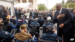 U.S. Defense Secretary Lloyd Austin, right, greets U.S. war veterans during a ceremony to mark the 79th anniversary of the liberation of France and Western Europe from Nazi control, at the American Cemetery in Colleville-sur-Mer, Normandy, France, June 6, 2023.