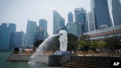 FILE - The Merlion statue spouts water at a park with the background of a business district in Singapore, Sept, 21, 2019. 