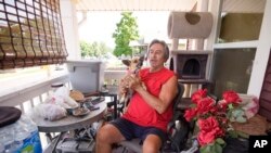 Ben Gallegos sits on the porch of his family's home in the Globeville neighborhood with his dog, Coca Smiles, as daytime temperature soars toward triple digits, July 27, 2023.