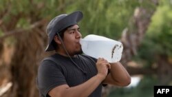 Brad Pablo drinks water while fishing at Christopher Columbus Park during a heat wave in Tucson, Arizona, on July 15, 2023.