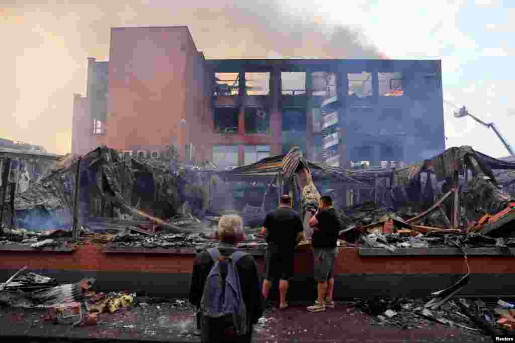 People look at a building of the Tessi group, burned during night clashes between protesters and police, following the death of Nahel, a 17-year-old teenager killed by a French police officer in Nanterre during a traffic stop, at the Alma district in Roubaix, northern France.