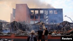 People look at a building of the Tessi group, burned during night clashes between protesters and police, following the death of Nahel, a 17-year-old teenager killed by a French police officer in Nanterre during a traffic stop, at the Alma district in Roubaix, northern France.