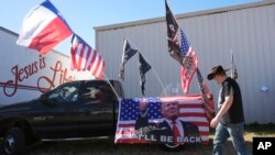 A participant passes flags and signage during a 'Take Our Border Back' rally, Feb. 3, 2024, in Quemado, Texas.