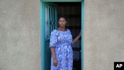 Jeanette Nyirabashyitsi, 45, stands in the doorway of her home at the Mybo reconciliation village in Nyamata, Rwanda, April 5, 2024.