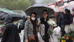 FILE - Iranian women walk through rain in a flower market, ahead of Nowruz, the Iranian New Year, in Tehran, Iran March 16, 2023.