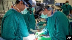 In this photo provided by Duke Health, surgeons Dr. Jacob Schroder, left, and Dr. Zachary Fitch perform a heart transplant at Duke University Hospital in Durham, N.C., in October 2022. (Shawn Rocco/Duke Health via AP)