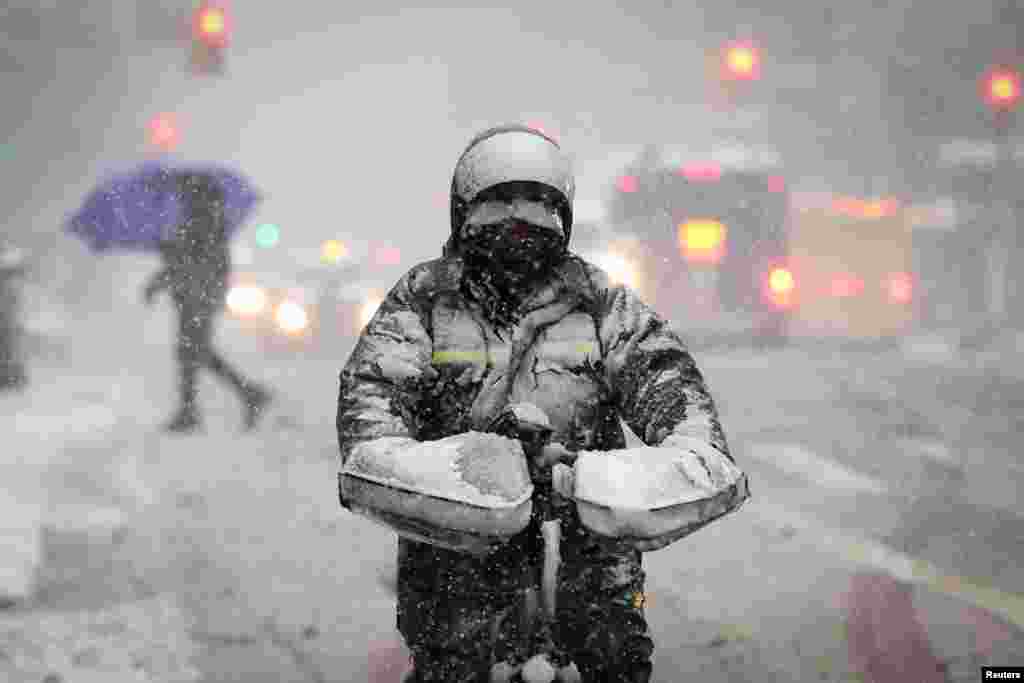 A delivery worker rides a bicycle on East 125th Street in heavy snowfall in Manhattan in New York City.