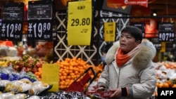 资料照：2024年2月8日，中国东部安徽省阜阳市，一名顾客在一家超市购买蔬菜和水果。(法新社）