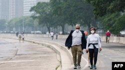 People walk along the shoreline of Lake Michigan with heavy smoke from the Canadian wildfires in the background, on June 27, 2023, in Chicago.