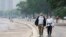 People walk along the shoreline of Lake Michigan with heavy smoke from the Canadian wildfires in the background, on June 27, 2023, in Chicago.