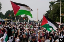Para pengunjuk rasa mengibarkan bendera Palestina sambil meneriakkan slogan-slogan dalam aksi damai dan doa mendukung warga Palestina di Gaza, di Jakarta, Minggu, 7 April 2024. (AP/Dita Alangkara)