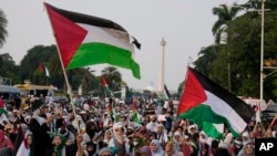 Para pengunjuk rasa mengibarkan bendera Palestina sambil meneriakkan slogan-slogan selama unjuk rasa dan doa untuk mendukung warga Palestina di Gaza, di Jakarta, 7 April 2024. (Foto AP/Dita Alangkara)