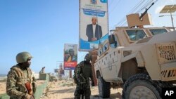 Des soldats de la paix ougandais de la Mission africaine de transition en Somalie (ATMIS) se tiennent à côté de leur véhicule blindé dans une rue de Mogadiscio, en Somalie, le 10 mai 2022.