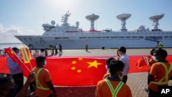 资料照：斯里兰卡港口工人在中国一带一路项目汉班托塔港手持中国国旗欢迎一艘中国考察船到港。（2022年8月16日）