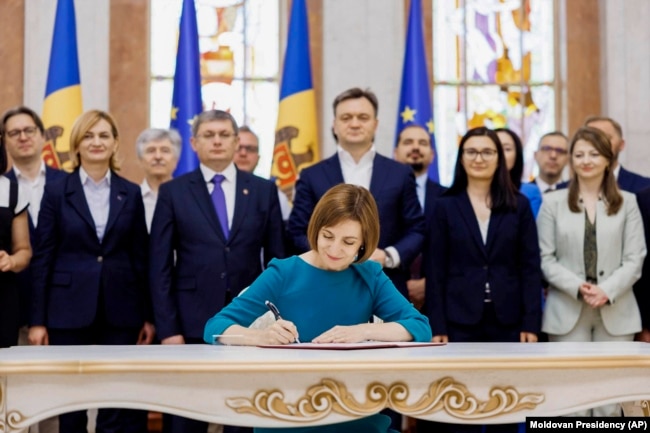 In this image released by Moldova's President, Moldova's President Maia Sandu signs the decree on initiating Moldova's EU accession negotiations in Chisinau, Moldova, June 21, 2024. (Moldovan Presidency via AP)